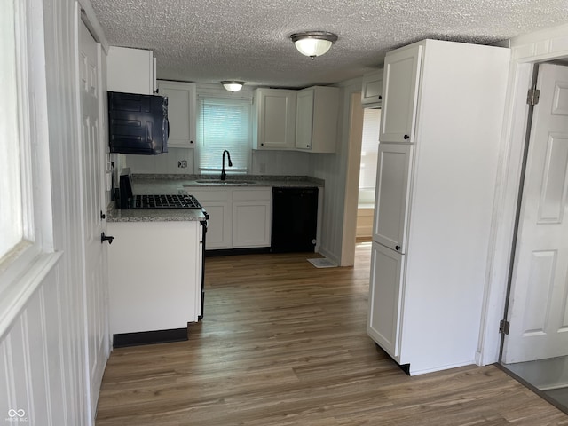 kitchen with a textured ceiling, white cabinets, wood finished floors, a sink, and black appliances