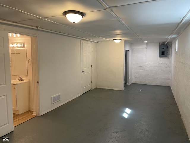 finished basement with electric panel, visible vents, and a sink