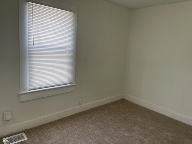 carpeted empty room featuring baseboards and visible vents