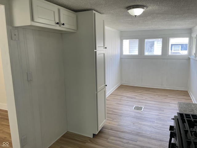 kitchen with visible vents, light wood-style floors, white cabinetry, and a textured ceiling