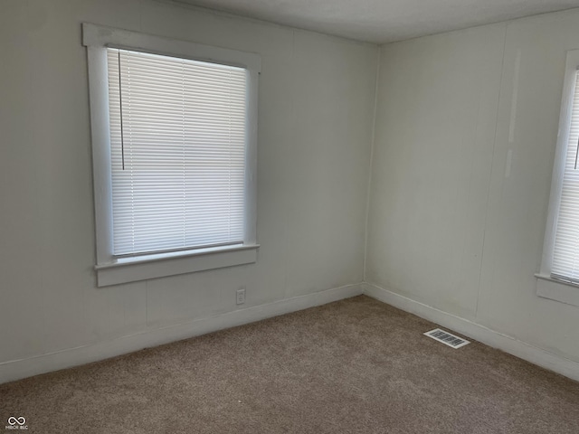 spare room featuring carpet, a healthy amount of sunlight, and visible vents