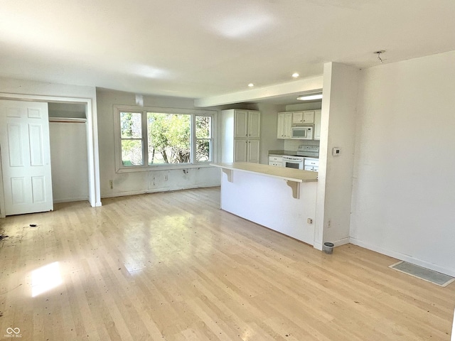7180 N State Road 42, Eminence, IN 46125 - kitchen featuring white appliances, light wood-type flooring, a peninsula, white cabinets, and a breakfast bar