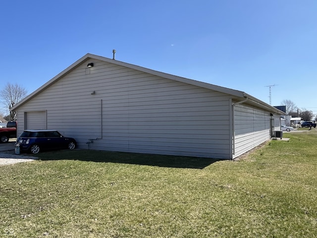 view of property exterior with a garage, central AC unit, and a yard