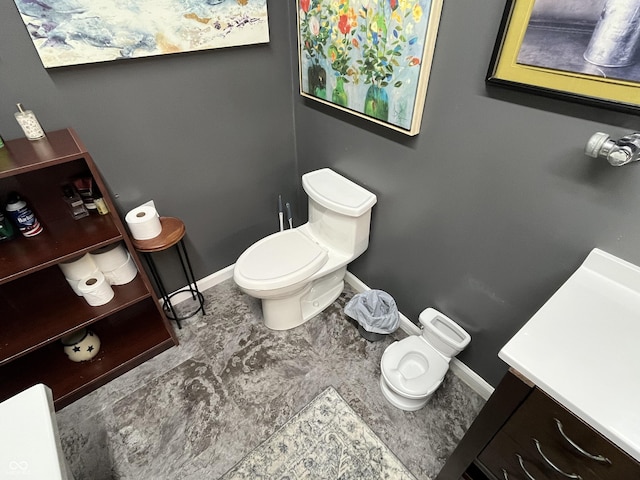 bathroom featuring baseboards, toilet, and vanity