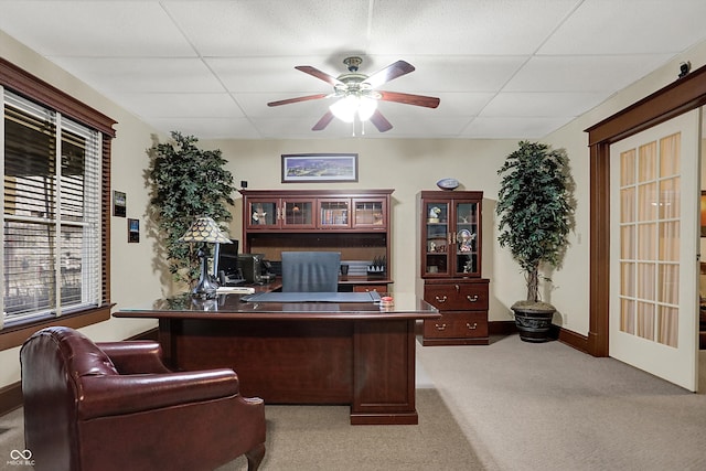 office area with baseboards, ceiling fan, carpet, and a drop ceiling