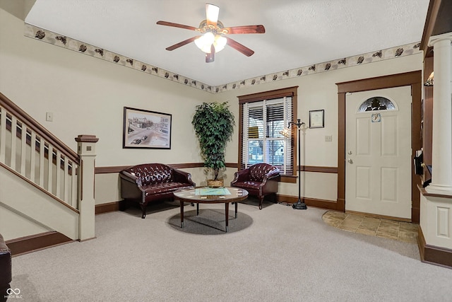 living area featuring ornate columns, carpet floors, stairs, and a ceiling fan