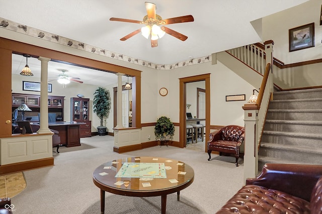 living room featuring ornate columns, baseboards, stairway, a ceiling fan, and light carpet
