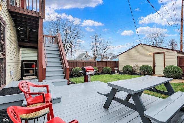 wooden deck featuring fence, stairs, a grill, an outdoor structure, and a yard