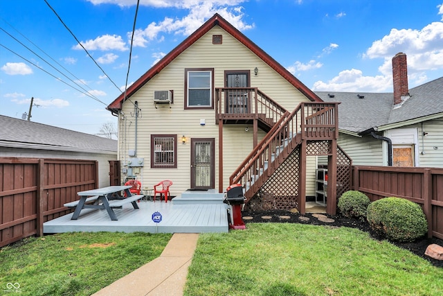 back of house featuring stairway, fence, an AC wall unit, a garage, and a lawn