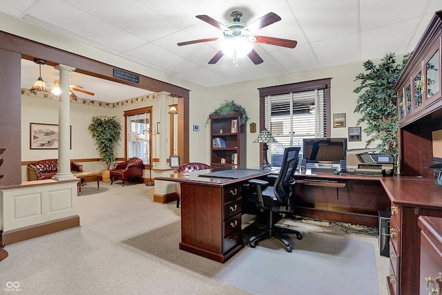 carpeted home office with decorative columns, ceiling fan, and a paneled ceiling