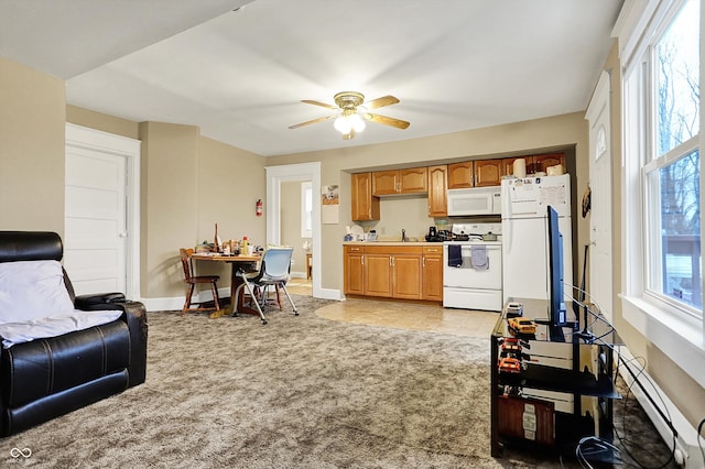 kitchen with a baseboard heating unit, white appliances, baseboards, a ceiling fan, and light carpet