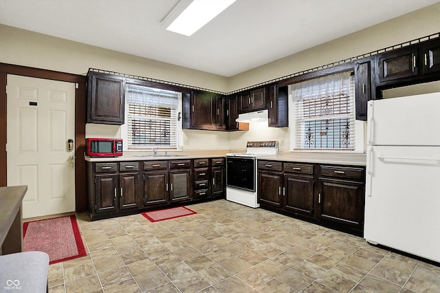 kitchen featuring light countertops, white appliances, under cabinet range hood, a sink, and dark brown cabinetry