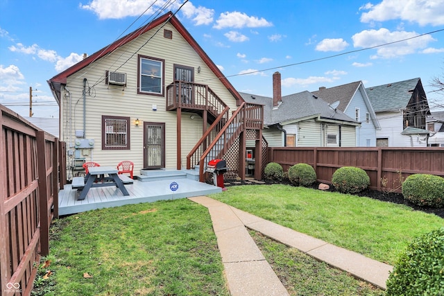 back of property with stairway, a deck, a fenced backyard, a wall mounted air conditioner, and a yard
