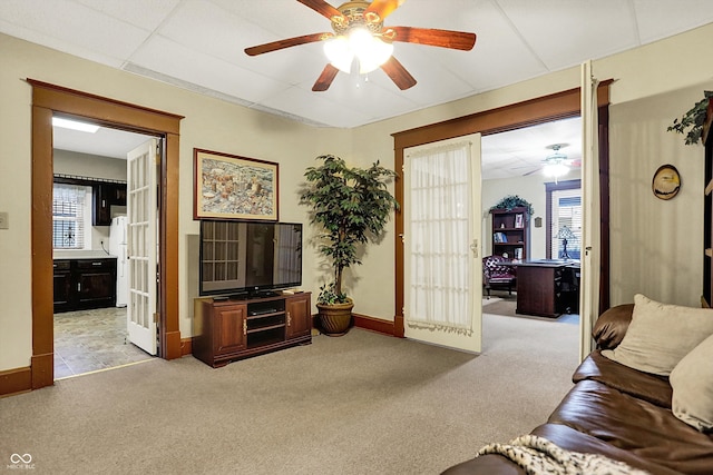 living room with french doors, a ceiling fan, baseboards, light colored carpet, and a drop ceiling