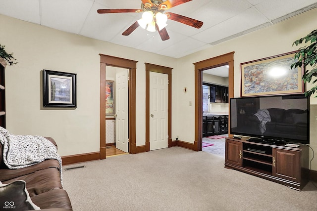 living room featuring baseboards, visible vents, a ceiling fan, light carpet, and a paneled ceiling