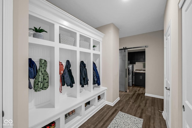 mudroom with washer / clothes dryer, a barn door, dark wood-style flooring, and baseboards