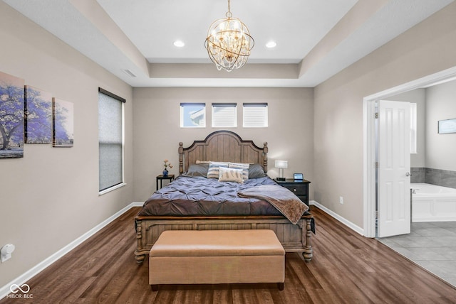 bedroom featuring a raised ceiling, wood finished floors, an inviting chandelier, and baseboards