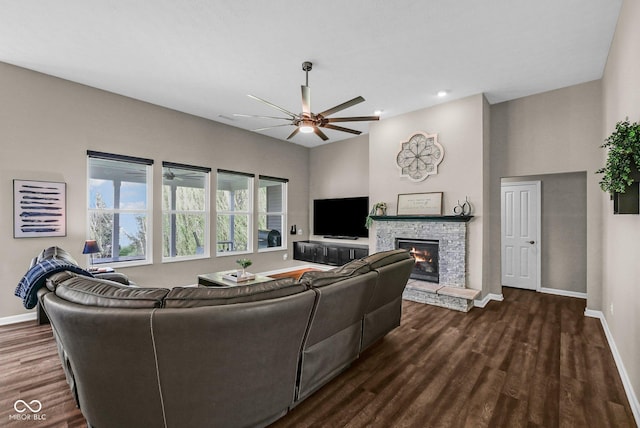 living area with dark wood-type flooring, ceiling fan, baseboards, and a fireplace