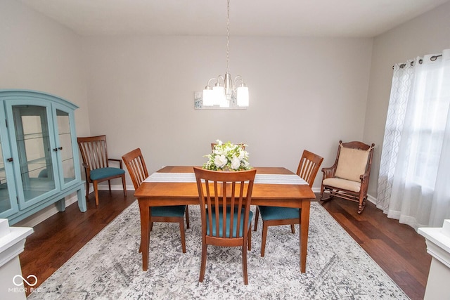 dining room with dark wood-type flooring, a wealth of natural light, baseboards, and a notable chandelier