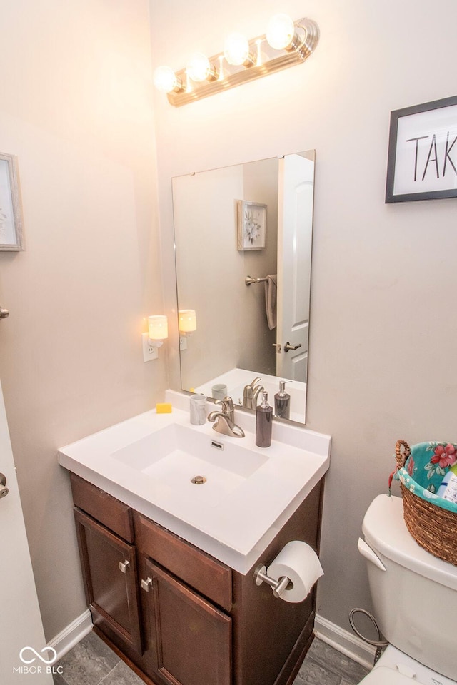 half bath featuring baseboards, toilet, and vanity
