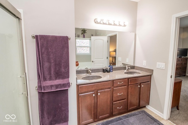 bathroom featuring baseboards, double vanity, connected bathroom, and a sink