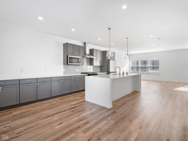 2578 Filson St, Carmel, IN 46032 - kitchen with gray cabinetry, stainless steel microwave, light wood-style flooring, and wall chimney exhaust hood
