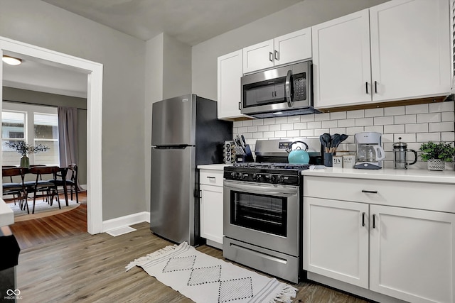 112 S Spencer Ave, Indianapolis, IN 46219 - kitchen with light countertops, white cabinetry, tasteful backsplash, wood finished floors, and stainless steel appliances