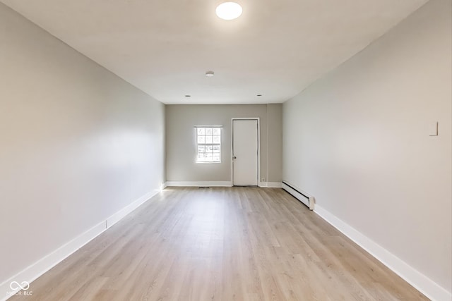 7906 E 21st St, Indianapolis, IN 46219 - empty room featuring light wood finished floors, baseboards, and a baseboard heating unit