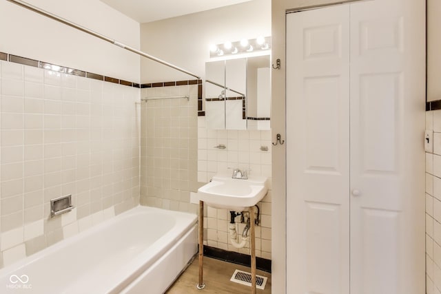 7906 E 21st St, Indianapolis, IN 46219 - full bathroom with tile walls, shower / washtub combination, visible vents, a closet, and wood finished floors
