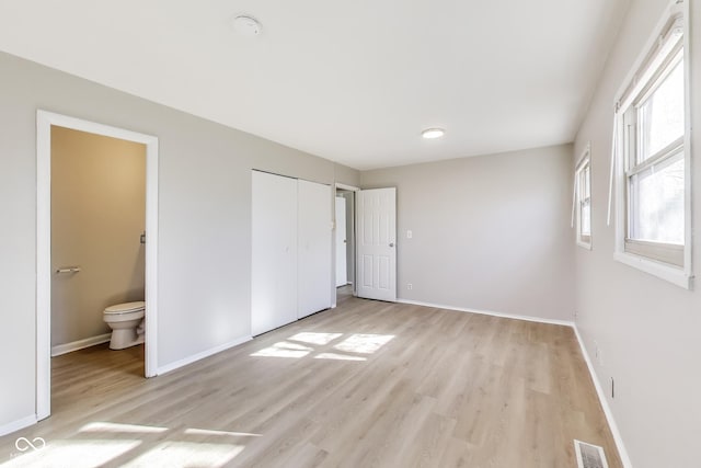 7906 E 21st St, Indianapolis, IN 46219 - unfurnished bedroom featuring baseboards, visible vents, light wood-style flooring, and ensuite bathroom
