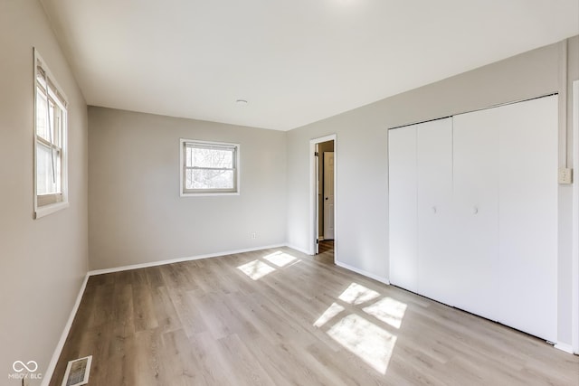 7906 E 21st St, Indianapolis, IN 46219 - unfurnished bedroom featuring baseboards, visible vents, a closet, and light wood-style flooring