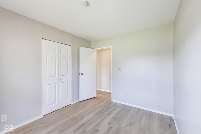 7906 E 21st St, Indianapolis, IN 46219 - unfurnished bedroom with light wood-style flooring, baseboards, and a closet