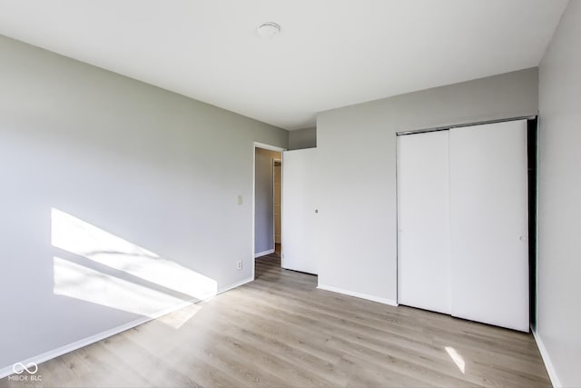 7906 E 21st St, Indianapolis, IN 46219 - unfurnished bedroom with baseboards, a closet, and wood finished floors
