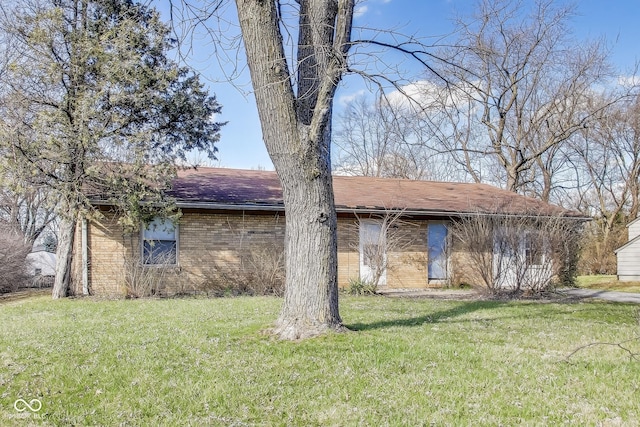 7906 E 21st St, Indianapolis, IN 46219 - view of front facade with brick siding, a front lawn, and roof with shingles