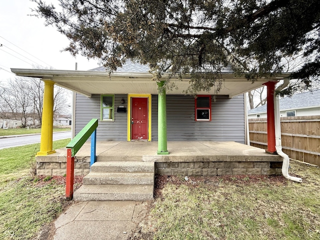 bungalow featuring fence, a shingled roof, and a porch