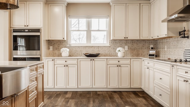 kitchen with wall chimney range hood, dark wood-style floors, and cream cabinets