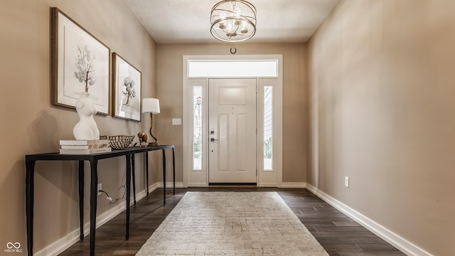 entrance foyer with a notable chandelier, baseboards, and dark wood finished floors