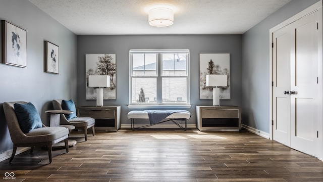 sitting room with a textured ceiling, baseboards, and dark wood finished floors