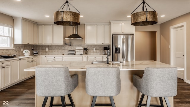 kitchen featuring dark wood-style flooring, stainless steel fridge with ice dispenser, light stone counters, and decorative backsplash