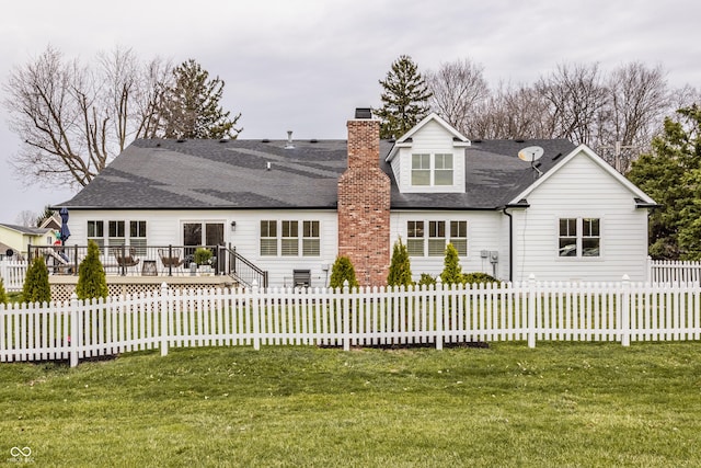 rear view of house featuring a lawn, a chimney, and a fenced backyard