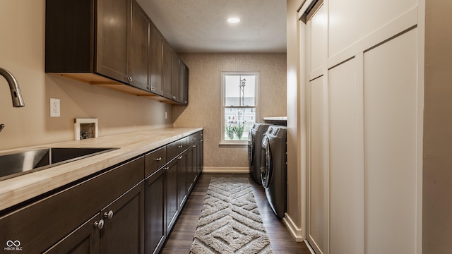 laundry room featuring a sink, dark wood finished floors, baseboards, independent washer and dryer, and cabinet space