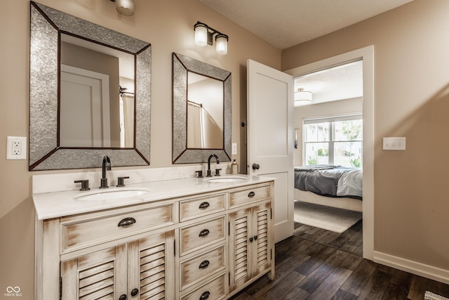 ensuite bathroom with ensuite bathroom, double vanity, a sink, and wood finished floors