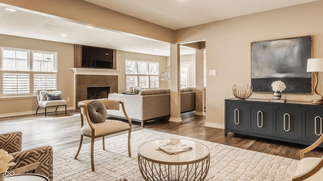 living room featuring dark wood-style flooring, a tile fireplace, baseboards, and recessed lighting