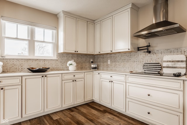 kitchen with light countertops, wall chimney exhaust hood, tasteful backsplash, cream cabinets, and dark wood-style flooring