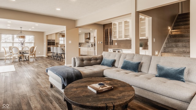 living area with baseboards, recessed lighting, wood finished floors, and stairway