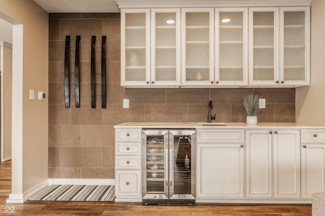 bar featuring baseboards, wood finished floors, a sink, beverage cooler, and indoor wet bar