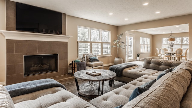 living area featuring a textured ceiling, wood finished floors, recessed lighting, and a tile fireplace