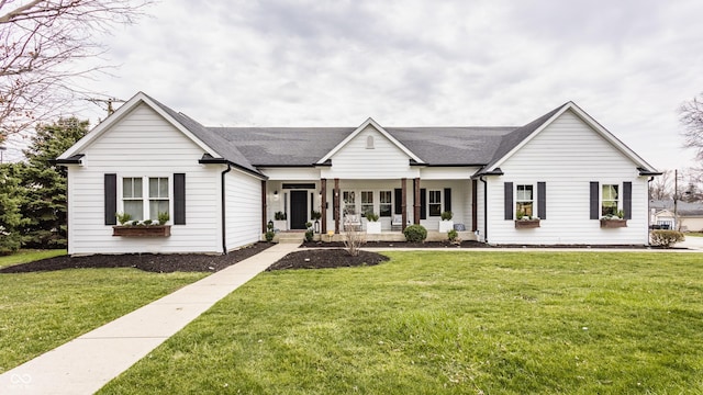 single story home featuring covered porch, a shingled roof, and a front yard