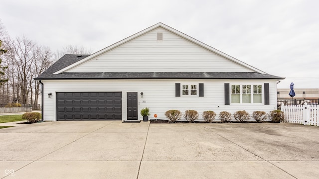 view of home's exterior with fence, roof with shingles, a garage, and concrete driveway