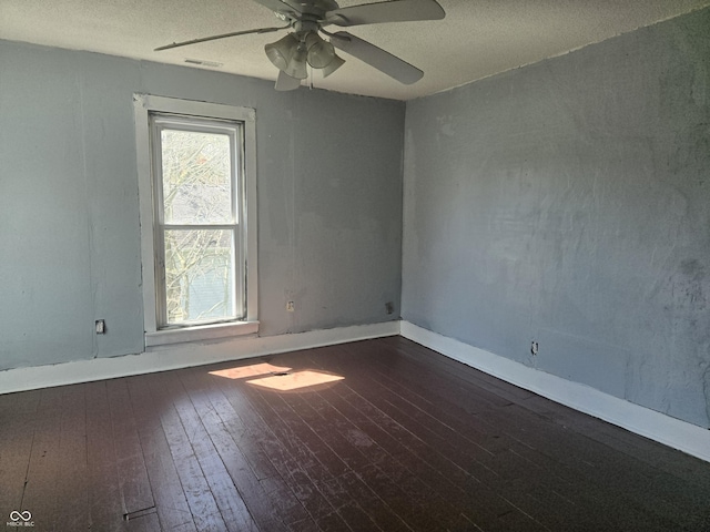 unfurnished room featuring dark wood-style floors, visible vents, a ceiling fan, and a textured ceiling